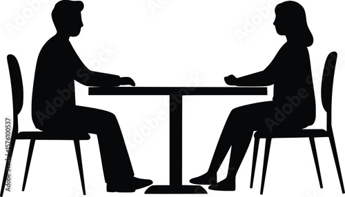 Silhouette showing two individuals seated at table engaged in conversation and negotiation in office setting