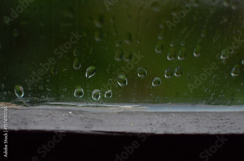 Rain drops on window, blurred green background