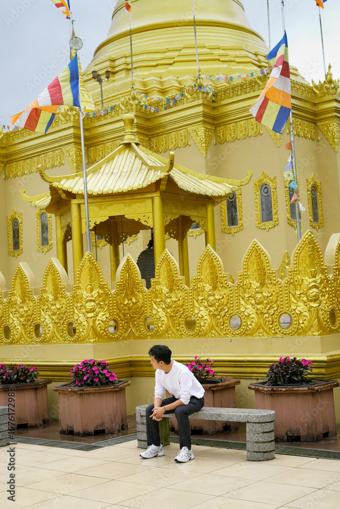 Fototapeta premium an asian chinese man Sitting by a Golden Ornate Temple with Decorative Surroundings