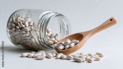 A wooden spoon spilling white beans from a glass jar, emphasizing freshness and healthy cooking ingredients.