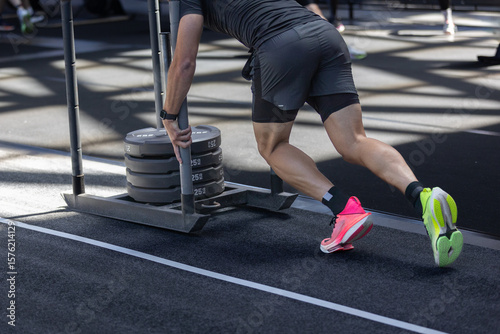 Athlete Pushing Weighted Sled On Track, Fitness Training With Heavy Sled In Facility