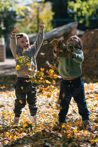 Two happy children throwing autumn leaves in the air while camping