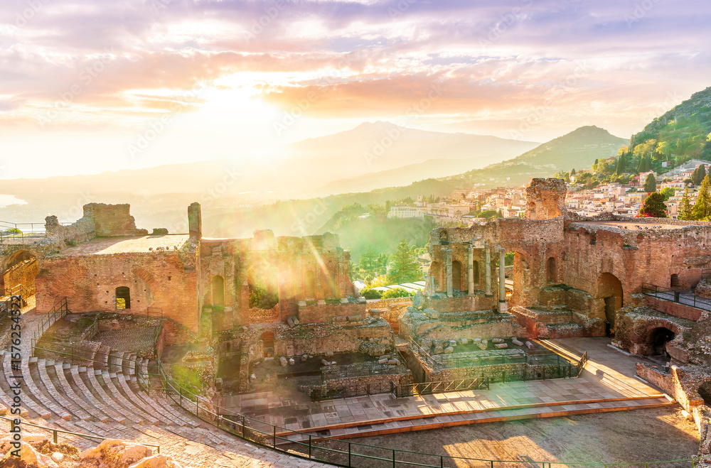 Obraz premium beautiful sunset landscape of evening ancient teatre of Taormina, Sicily in Italy with cityscape and evening mopuntains on background. Ancient archeological landscape of Italy