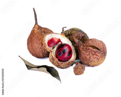 Several dried nutmegs with one open revealing the nutmeg seed and bright red mace, with dried leaves as decoration, isolated on a white background
