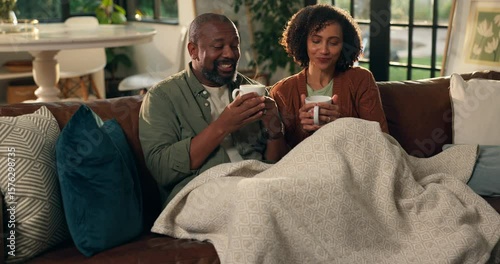 African couple, laughing and relax with coffee on sofa for bonding, funny story and cozy together. Love, mature people and happy with blanket in house for weekend break, conversation and connection