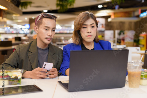 Gender diverse coworker business team eating salad and working digitally