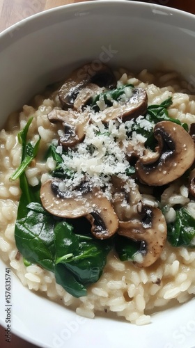 Creamy risotto features fresh spinach and mushrooms, served in a rustic bowl. This traditional Italian dish highlights the rich flavors and textures of authentic ingredients