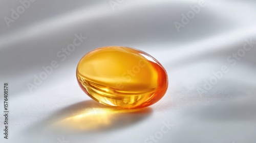 Close-up of a glossy amber-colored gel capsule supplement on smooth surface