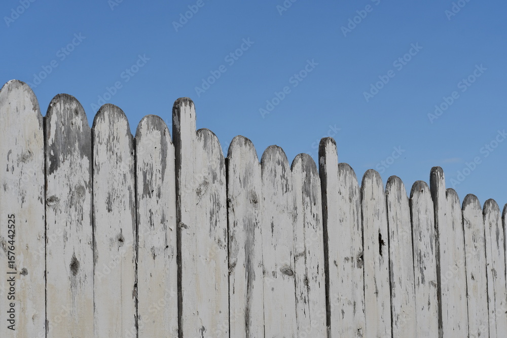 Obraz premium Nice older white picket fence pointing towards the clear blue sky.