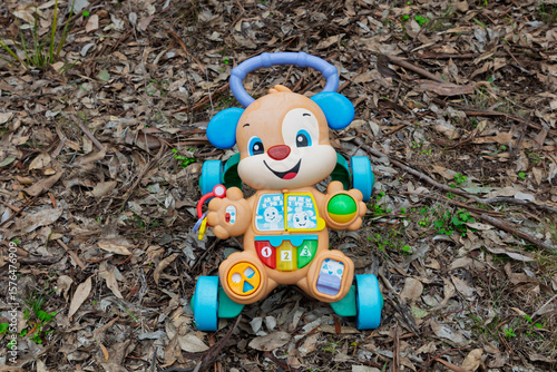 Billede på lærred Photograph of a small plastic colourful toy that has been discarded on the ground on dry tree leaves in a remote forest