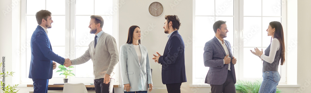 Happy friendly confident business people meeting in office, greeting with handshakes, talking, smiling, business leader congratulating colleague, shaking hand, professional corporate atmosphere Happy friendly confident business people meeting in office, greeting with handshakes, talking, smiling, business leader congratulating colleague, shaking hand, professional corporate atmosphere