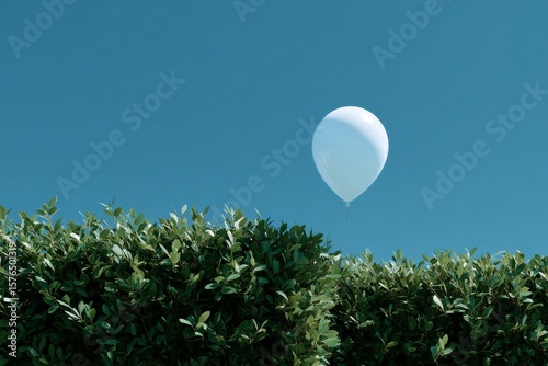 Blue Balloon Floats Above Green Hedge Under Clear Sky in Bright Daylight
