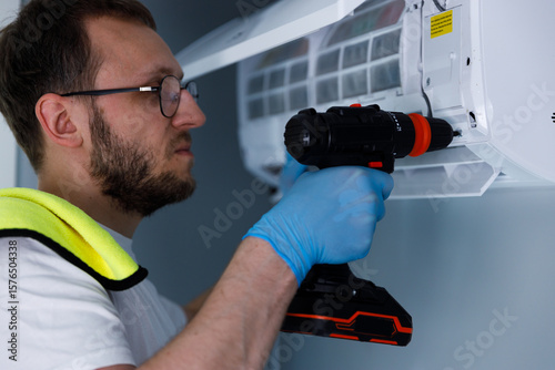 Professional Technician Repairing Air Conditioning Unit with Power Drill for Efficient Maintenance and Perfect Cooling Performance in a Residential Environment