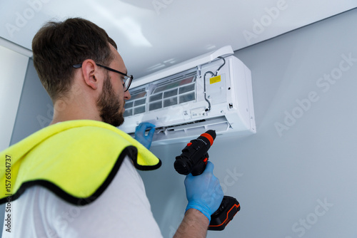 Professional technician performs routine maintenance on a modern air conditioning unit mounted on a wall, ensuring optimal performance in a comfortable indoor environment.