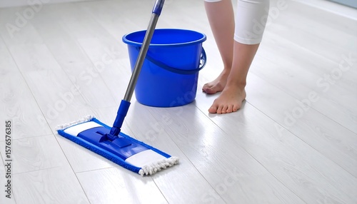 Woman mopping light-colored floor with blue mop and bucket