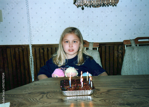 Angsty tween girl and a birthday cake at the kitchen table, circa 1992. 90s children. Image is a vintage scan and may have imperfections