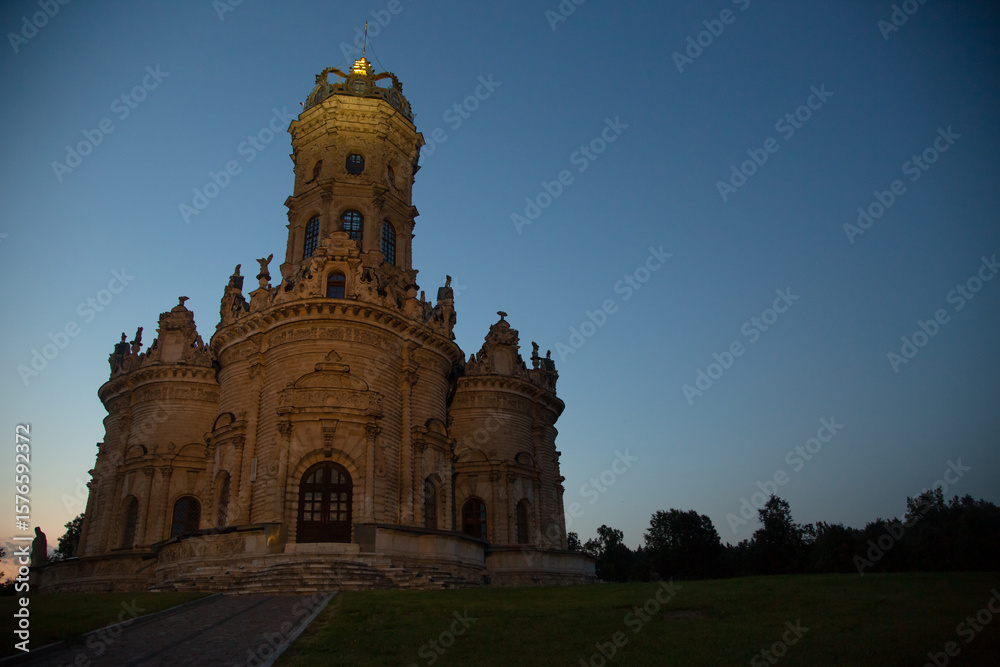Fototapeta premium Beautiful entrance door with staircase to baroque medieval style old church building on nature bright evening light on sunset bright blue sky. Europe religion architecture building
