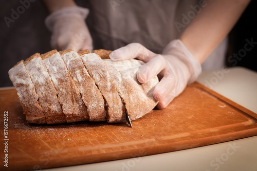 Φωτογραφία Baker Slicing Freshly Baked Bread on a Wooden Cutting Board