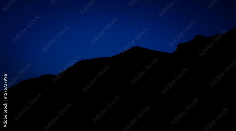 Fototapeta premium Mountain range silhouetted against inky sky