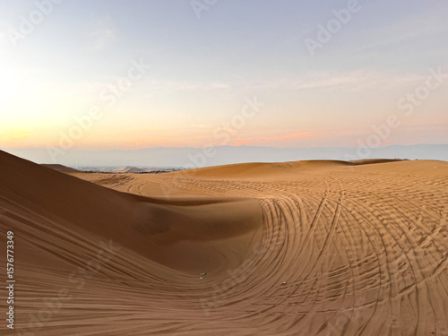 фотографія Photo of desert at sunrise sunset hour with dune buggy tires tracks in the sand
