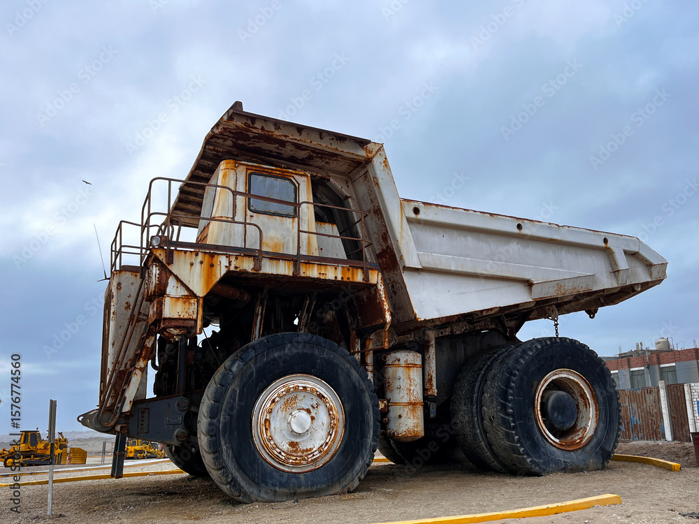 Obraz premium Large grey old quarry dump truck. Big green rusty mining truck out of work standing for exhibition on the coast of Peru in San Juan de Marcona. Mining truck 