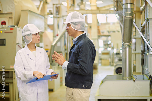 食品工場で打ち合わせをする男女スタッフ