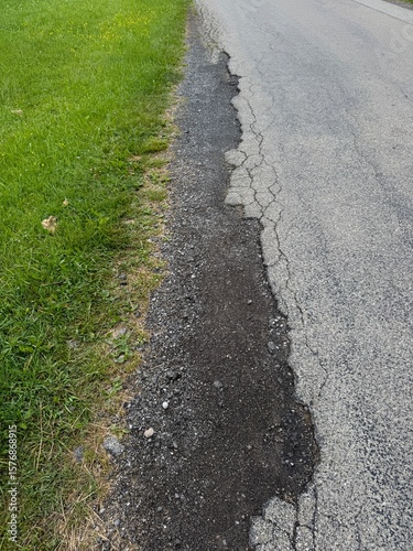 Road with a crack in it and grass growing on the side
