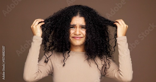 Portrait, hair and woman in studio with damage, frizz problem and dry texture on brown background. Hairdresser, salon and person with for haircare treatment, curly routine and grooming for health