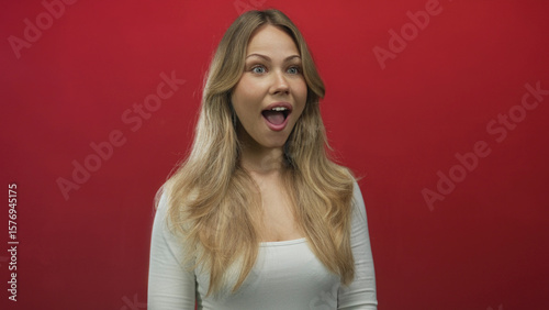 Woman with long blonde hair and open mouth shows surprise in studio portrait; wonder amazement curiosity excitement.