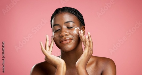 Fotografi Black woman, lotion and skincare with face cream in studio for moisturizer on a pink background