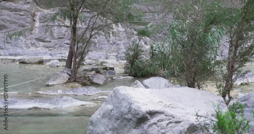 Full shot of mexican photographer walks over a rock by a river and take a photo