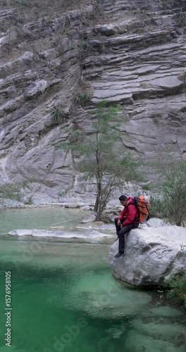 Vertical video of thoughtful young mexican man sitting by a water pool