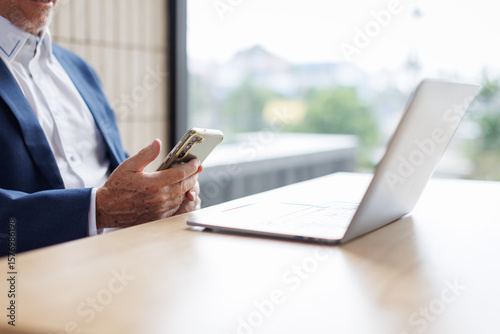 Portrait of a cheerful mid adult businessman using phone for investment plan chatting contact Investor searching for informationat at workplace office. connecting people concept