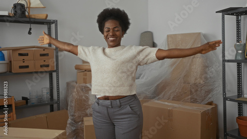 Young woman rejoicing in modern living room surrounded by unpacked boxes denotes new beginning and excitement within her urban apartment environment.