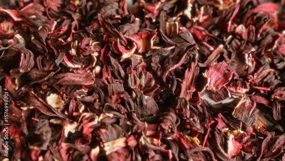 Obraz premium Dried hibiscus petals forming a colorful and textured background showcasing the vividness of the dried flower pieces