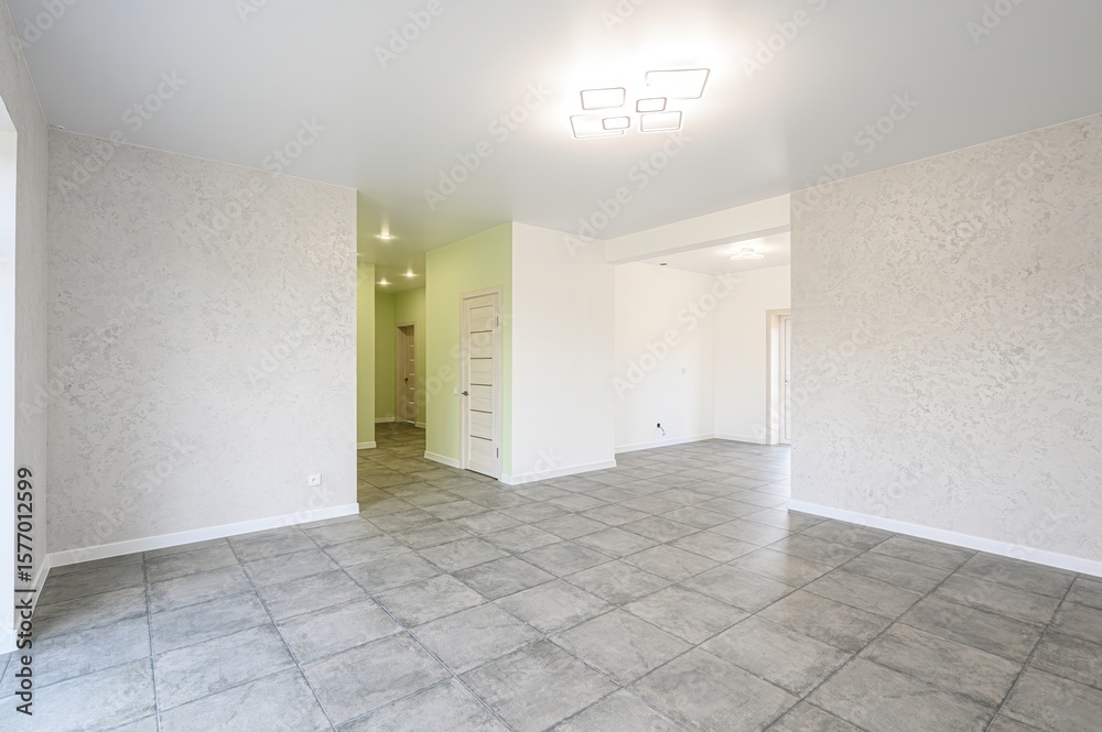 Fototapeta premium Bright, empty room with gray tile floor. Textured walls and modern ceiling light. Freshly painted interior