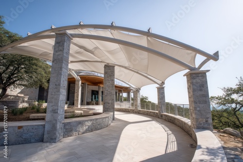 A grand hillside property an arched pavilion with tensile fabric canopy stone columns on a curved overlook photographed