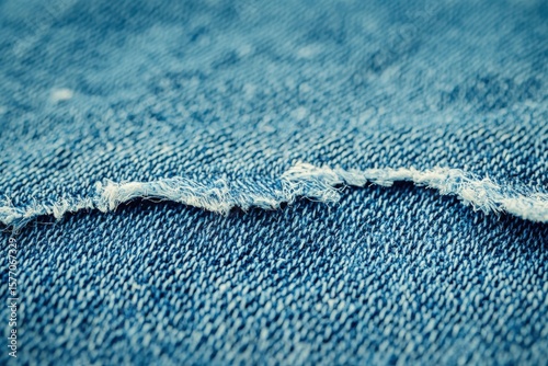 Close-up of distressed denim fabric with frayed edge