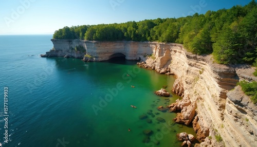 Lake Superior coastline with tranquil beach scene, light brown rocks, dark brown cliffs, clear blue ocean. Scenic landscape of Pictured Rocks National Lakeshore in Michigan. Few people on shoreline