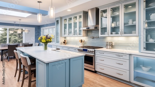 Ice blue kitchen with glass upper cabinets, stainless fixtures, and open concept flowing into luxury living space,