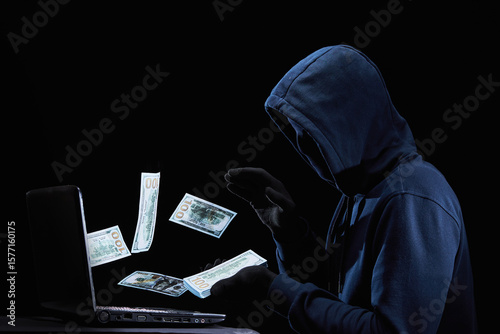 Obraz na plátně A masked hacker with a laptop fraudulently steals money through the Internet