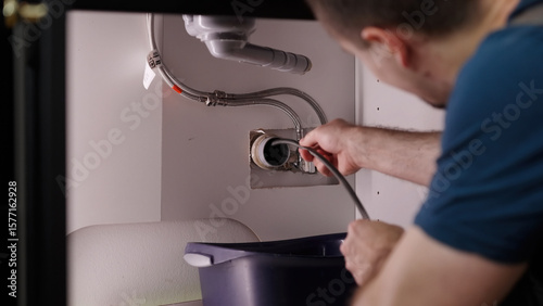Plumber drill through clogged sink pipes with spring tube tool