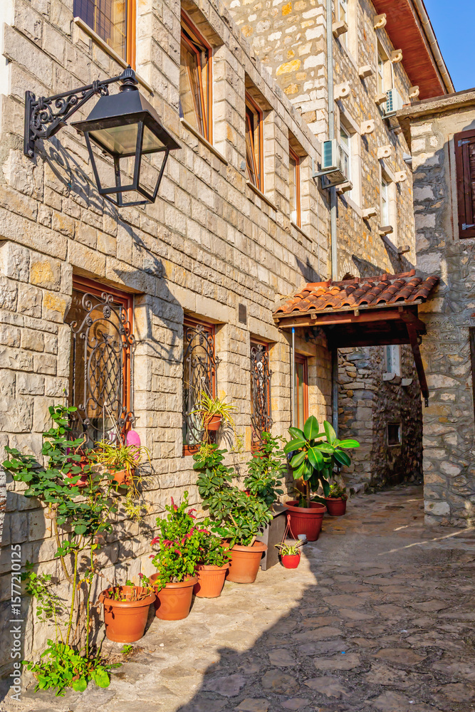 Obraz premium Traditional stone house with potted plants in sunlit alley of Ulcinj Old Town, Montenegro