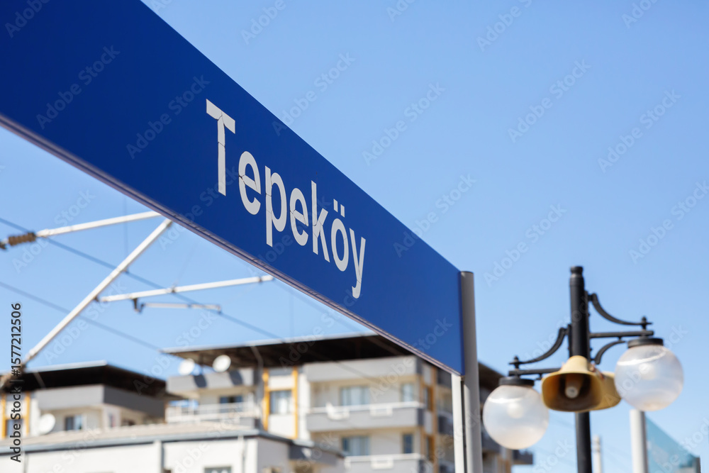 Obraz premium Tepekoy train station sign with residential buildings in background on a sunny day in Izmir, Turkey