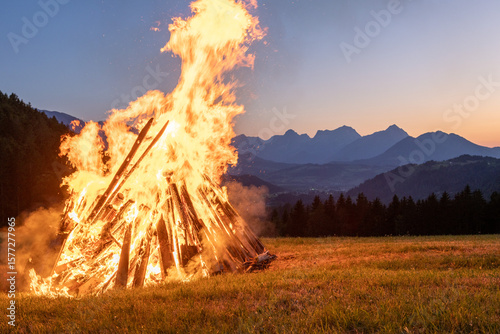 Solstice bonfire with sunset in the background in the Alps