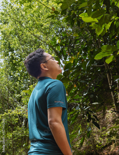 A man standing in the forest, solo travel, connecting with nature and him inner self, forest bathing, mindfulness. Green life concept, sustainable development. Net Zero, Carbon Neutral.