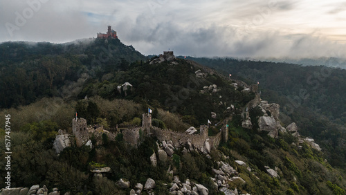 Aerial view of the ancient walls of Castelo dos Mouros snaking across the landscape toward the Pena Palace shrouded in mist, Sintra, Lisboa, Portugal.