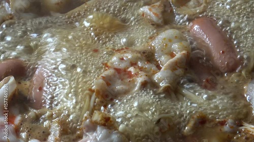 Boiling mala pork hot pot broth soup. Close up pork, mushroom, sausage.