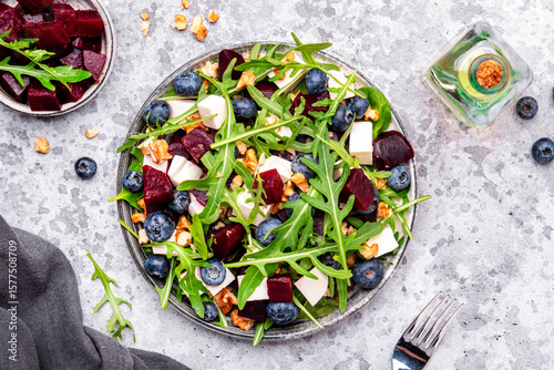 Gourmet salad with beet, blueberries, cheese, arugula and walnuts, gray table background, top view