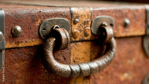 Close-up of a rusty metal handle on an aged wooden trunk.